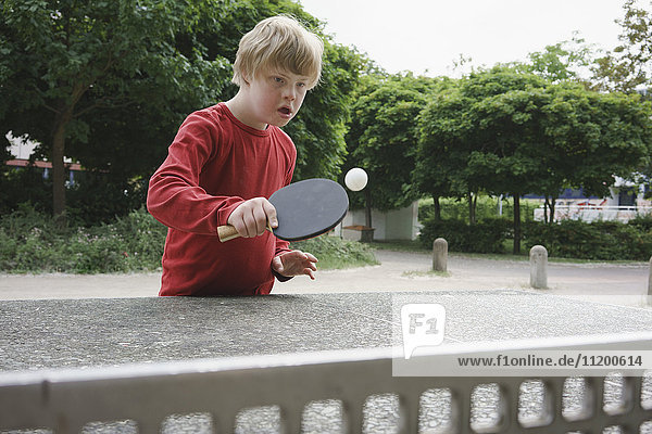 Behinderter Junge spielt Tischtennis im Park