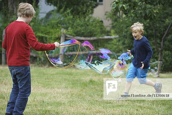 Glückliche Brüder spielen mit Seifenblase im Hinterhof
