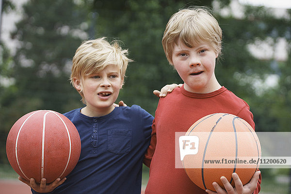 Brüder stehen mit den Armen herum und halten Basketbälle im Park.