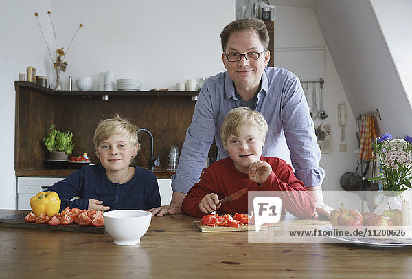 Porträt eines Vaters mit Söhnen am Tisch in der Küche