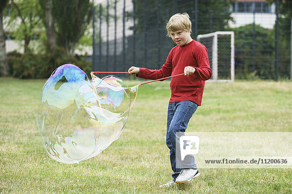 Behinderter Junge spielt mit Seifenblasen im Park