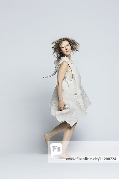 Portrait of beautiful woman wearing dress spinning against white background