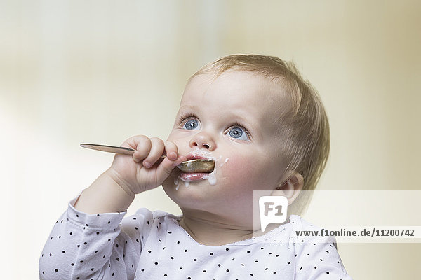 Close-up of girl with messy face holding spoon in mouth