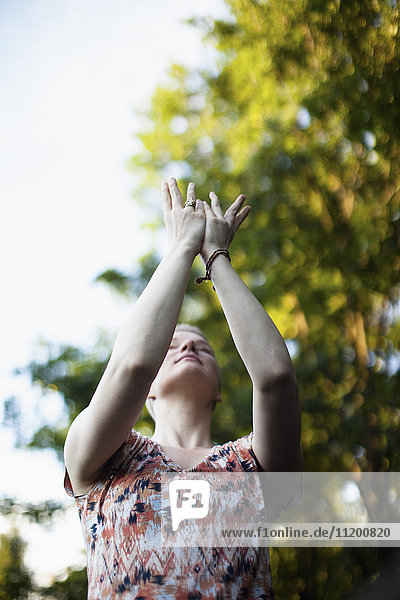 Low angle view of woman exercising Tai Chi against trees