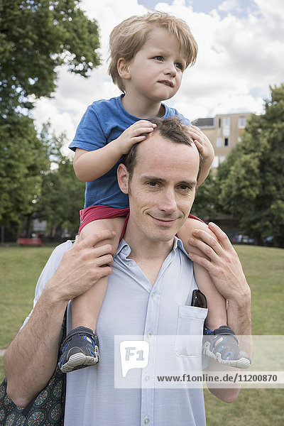 Portrait of father carrying son on shoulders at park