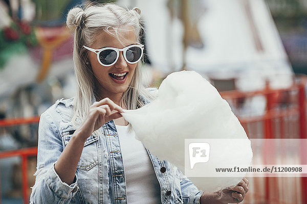 Fashionable young woman wearing sunglasses while eating cotton candy outdoors