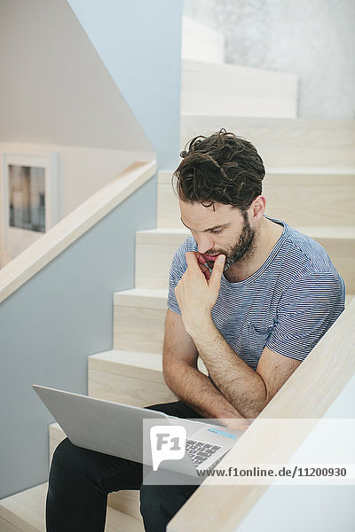 Man with laptop sitting on stairs