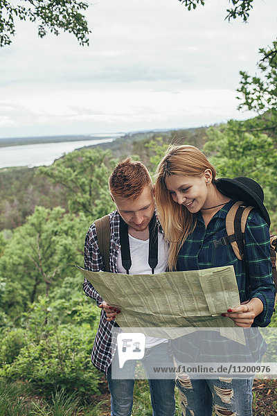 Smiling couple reading map while hiking in forest