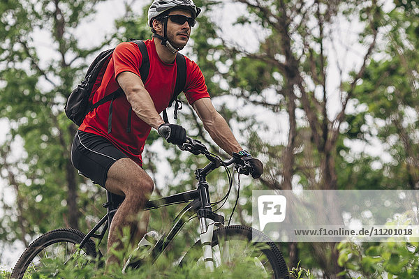 Confident man riding mountain bike in forest