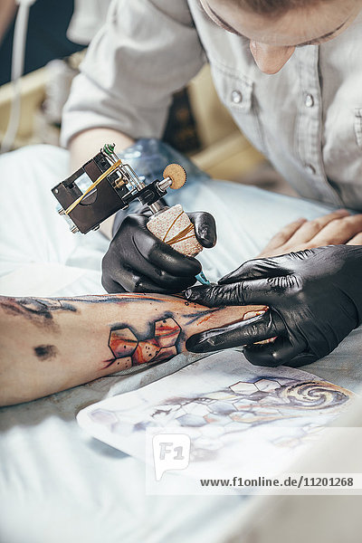 Konzentriertes Künstler-Tätowierdesign auf Menschenhand