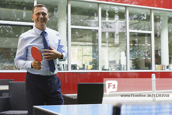 Lächelnder Geschäftsmann beim Tischtennisspielen im Kreativbüro