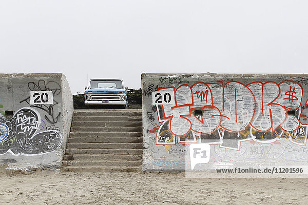Stufen inmitten von Graffiti an Wänden  die gegen den klaren Himmel in Richtung Auto führen.