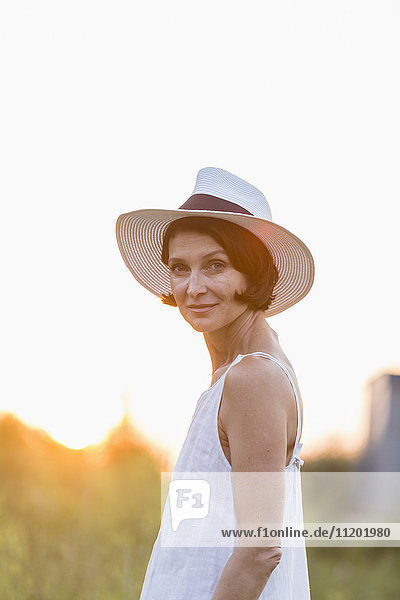 Porträt einer selbstbewussten Frau mit Hut vor klarem Himmel