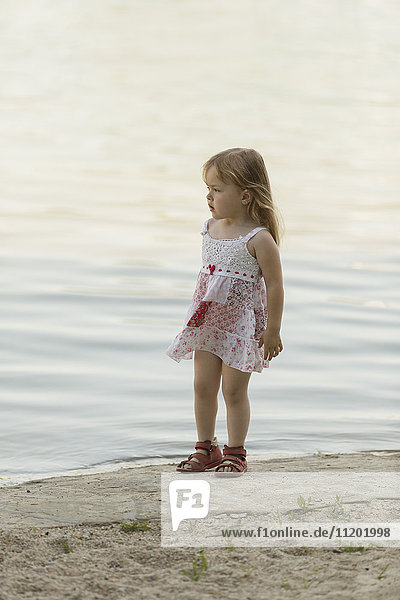 Nachdenklich süßes Mädchen am Seeufer stehend