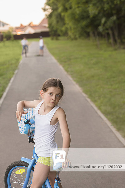 Portrait of girl with bicycle on road at park