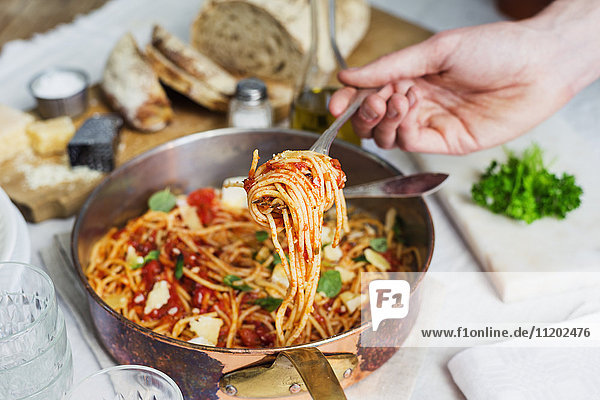 Hand holding spaghetti on fork