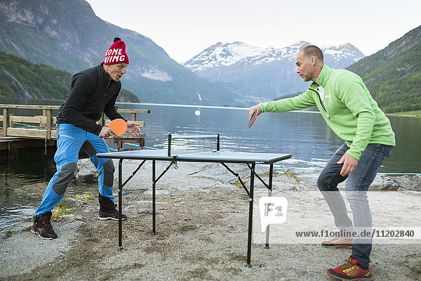 Men playing table tennis at lake