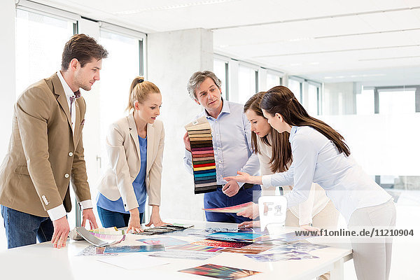 Ein Team von Designern mit Mustern diskutiert am Tisch im neuen Büro