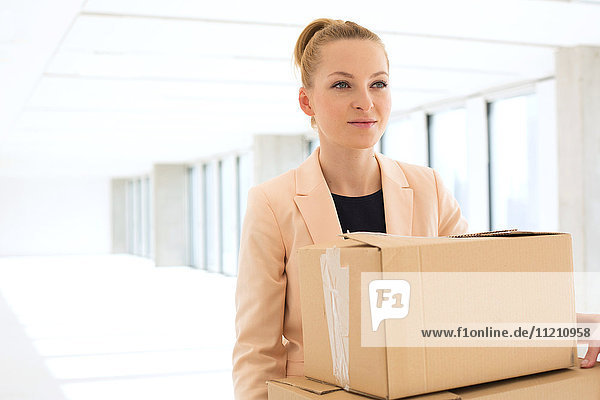 Junge Geschäftsfrau trägt Kartons in ihr neues Büro