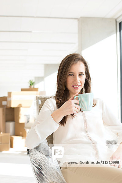 Portrait of confident young businesswoman drinking coffee in new office