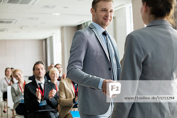 Selbstbewusster Geschäftsmann bei der Begrüßung eines Redners während eines Seminars