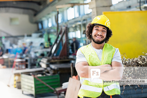 Portrait of smiling male manual worker standing arms crossed in metal industry