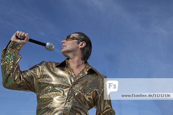 Ein Elvis-Imitator singt in ein Mikrofon