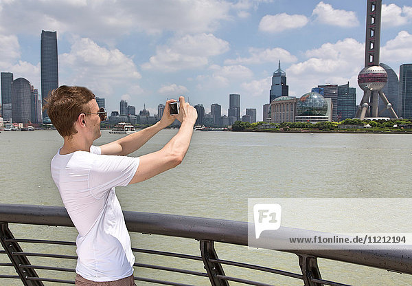 Caucasian man taking a photo of the Shanghai Skyline