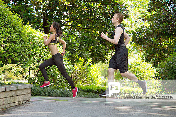 Side view of Multi ethnic couple running in park