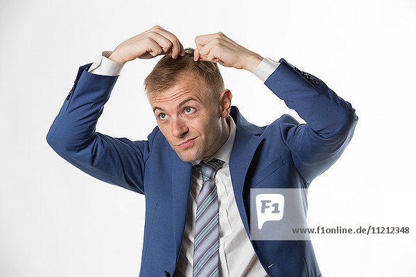 Businessman checking his hair indicating hair loss