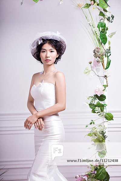Portrait of elegant bride standing against white wall