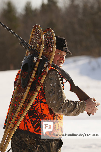 Snowshoe Hare Hunter Carries Snowshoes On His Gun Barrel