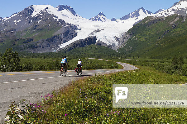 A pair of bikers ride the Richardson Hwy with Worthington Glacier in the background  Southcentral Alaska  USA