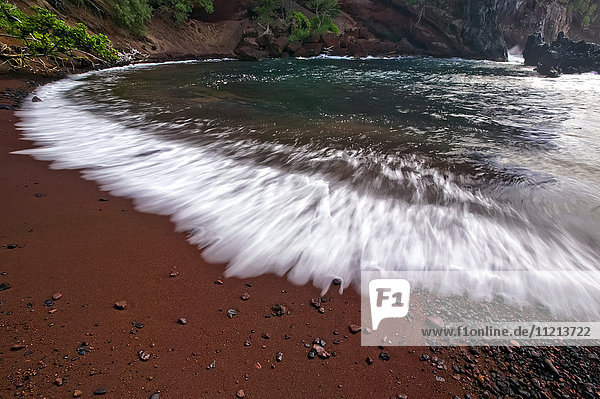 Wasser  das an den roten Sandstrand entlang der Küste einer hawaiianischen Insel gespült wird; Maui  Hawaii  Vereinigte Staaten von Amerika'.