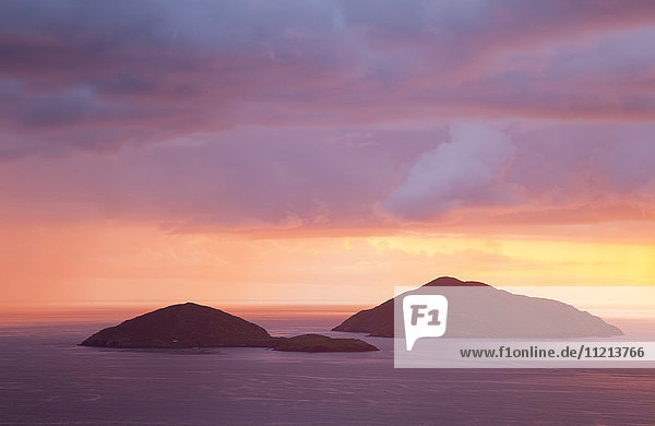 Kleine Inseln im Meer mit einem dramatischen  farbenfrohen Himmel bei Sonnenuntergang; Caherdaniel  County Kerry  Irland'.