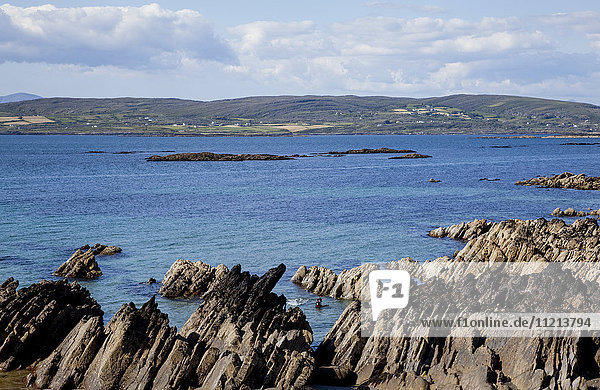 Zerklüftete Felsen entlang der Küstenlinie mit Hügeln in der Ferne  in der Nähe von Eyeries; Grafschaft Cork  Irland'.