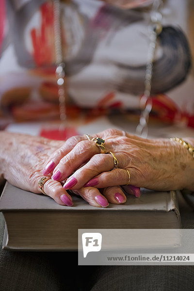 'A senior woman's hands folded on top of a hard cover book; Devon  Alberta  Canada'