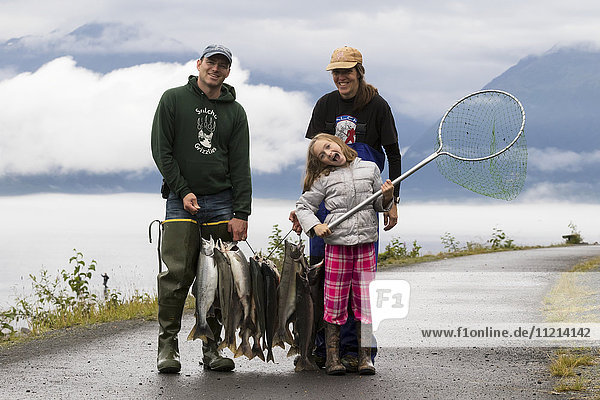 Young family show off their dipnet catch on a walking path in Valdez  Southcentral Alaska  USA