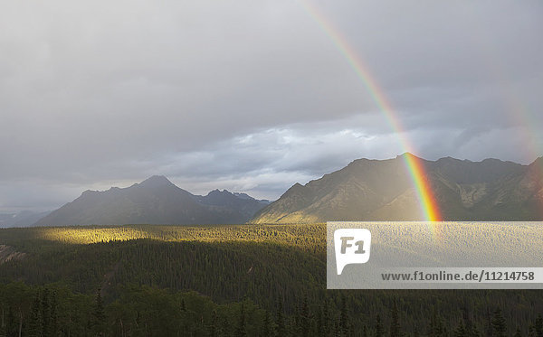 'A rainbow shines brightly over mountains east of Palmer in summertime  South-central Alaska; Alaska  United States of America'