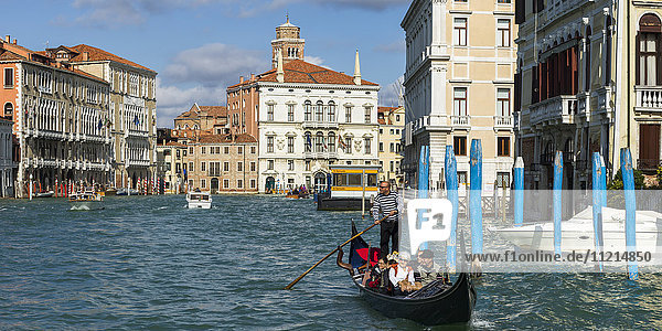 Ein Gondoliere  der eine Gondel mit Passagieren in einem Kanal rudert; Venedig  Italien'.