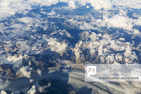 Luftaufnahme von Wolken  die sich zwischen den schneebedeckten Gipfeln der Alaska Range winden  im Inneren Alaskas; Alaska  Vereinigte Staaten von Amerika'.