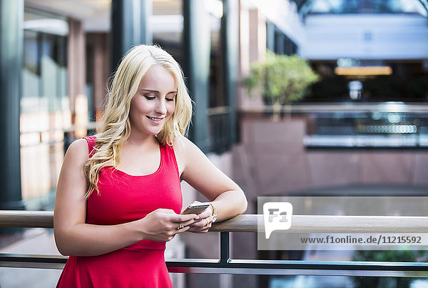 Eine hübsche junge Geschäftsfrau aus dem Millennium  die in einer Pause in einem Bürokomplex eine SMS schreibt; Edmonton  Alberta  Kanada