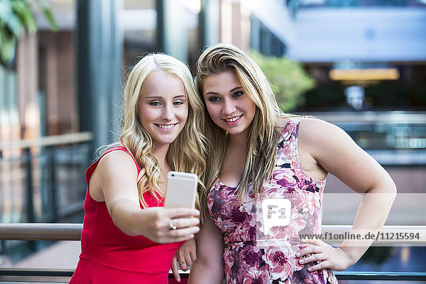 Zwei schöne junge Frauen machen ein Selbstporträt während einer Pause an ihrem Arbeitsplatz; Edmonton  Alberta  Kanada'.
