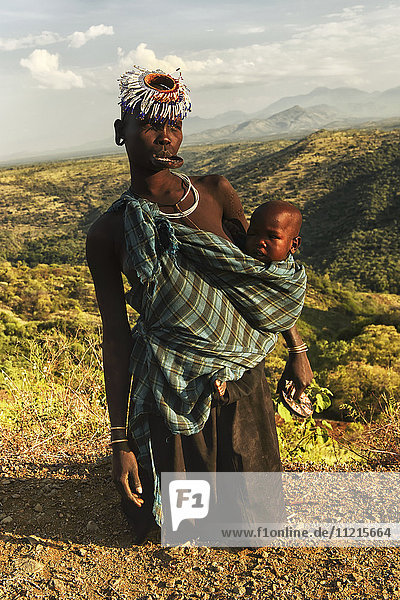 'Tribesman with baby and plated lip  Omo Valley; Ethiopia'