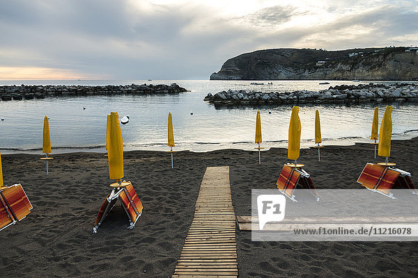 Holzpromenade und gelbe Sonnenschirme am Strand von Sant Angelo; Sant Angelo  Ischia  Kampanien  Italien'.