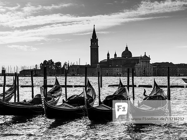Gondeln  die in einer Reihe auf dem Wasser vertäut sind  mit dem Markusplatz in der Ferne; Venedig  Italien'.