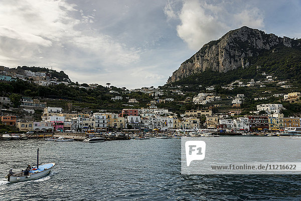 Ein Boot fährt auf den Hafen mit den bunten Gebäuden entlang der Uferpromenade zu; Capri  Kampanien  Italien