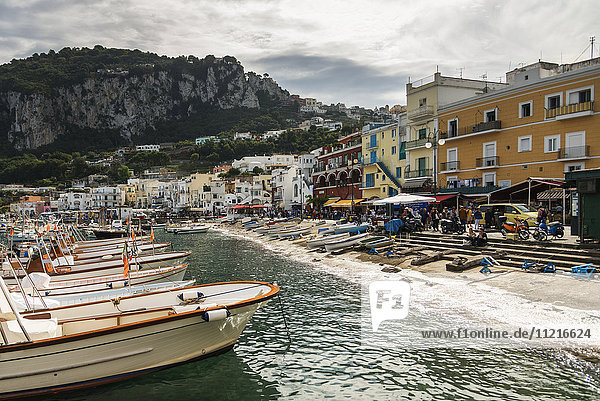 Aneinandergereihte Boote im Hafen mit farbenfrohen Gebäuden entlang der Uferpromenade; Capri  Kampanien  Italien