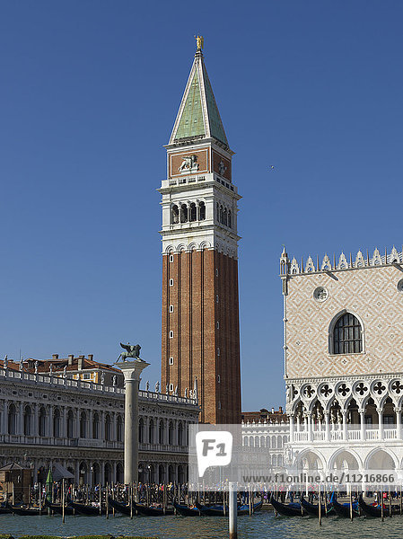Gondeln in einer Reihe in einem Kanal mit dem Turm auf dem Markusplatz und dem Dogenpalast; Venedig  Italien