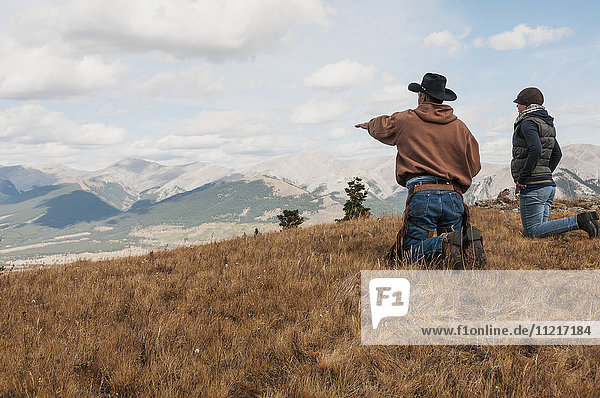 Cowboy und eine Frau auf den Knien mit Blick auf die felsigen Berge  Ya-Ha-Tinda Ranch; Alberta  Kanada